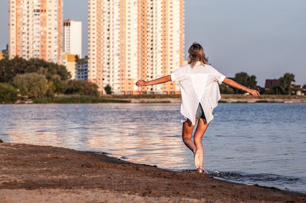 Een jonge vrouw die door de rivier loopt tegen de achtergrondfoto een mooie gelukkige blonde in witte kl...