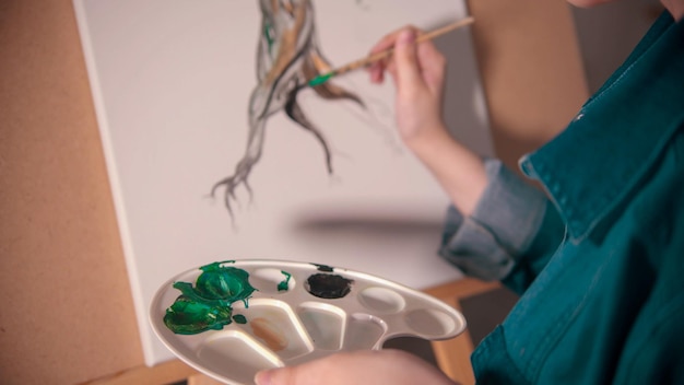 Een jonge vrouw die een boomstam schildert in een donkerdere kleur