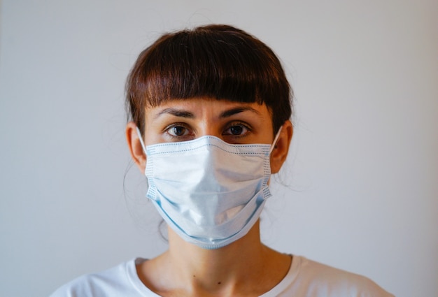 Een jonge vrouw die een medisch masker en beschermende chirurgische steriele handschoenen aan haar hand draagt