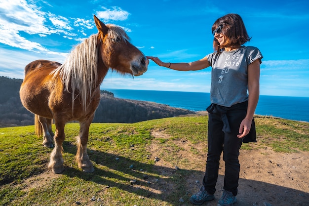 Een jonge vrouw die een vrij paard begroet van de berg Jaizkibel bij San Sebastian, Gipuzkoa. Spanje
