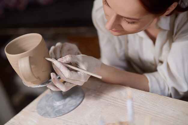 Een jonge vrouw die het aardewerk schildert en er betrokken uitziet