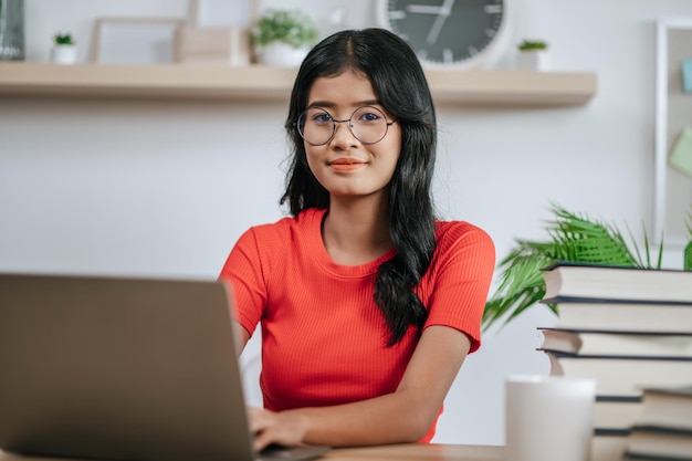 Een jonge vrouw die met een laptop op tafel werkt.