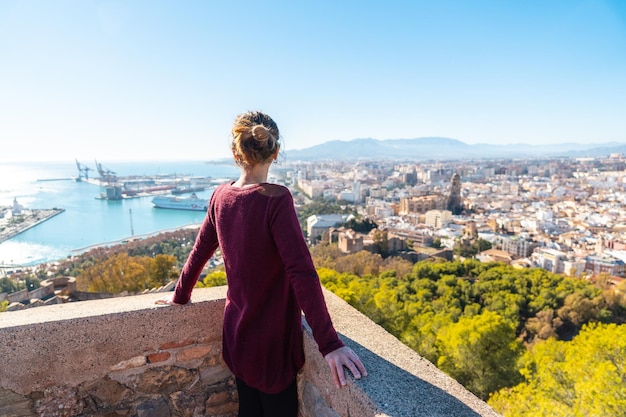 Een jonge vrouw die naar de stad kijkt vanaf de muur van het Gibralfaro-kasteel in de stad Malaga, Andalusië. Spanje