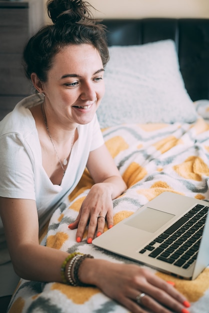 Een jonge vrouw die online met gezichtstijd op laptop spreekt.