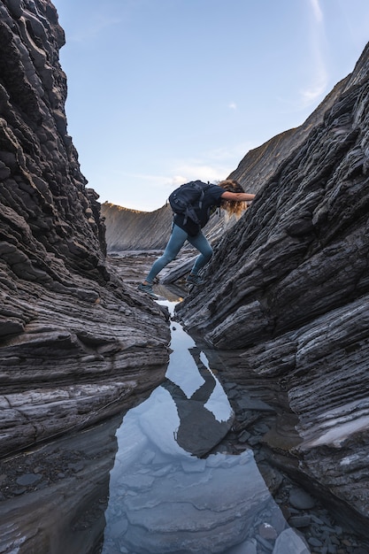 Een jonge vrouw die op een ochtend het Sakoneta kust geopark tussen stenen verkent