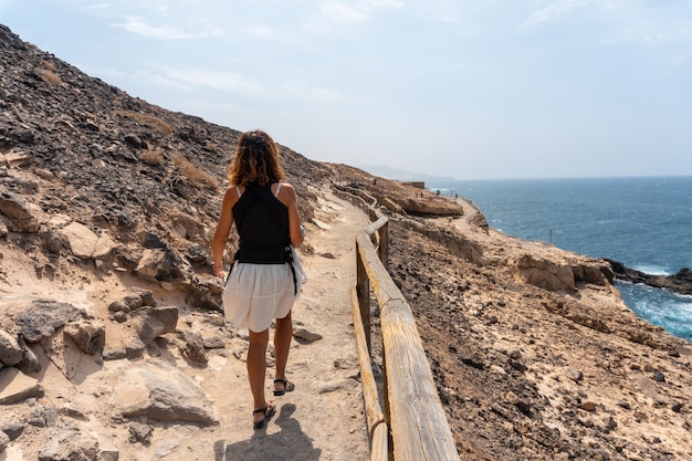 Een jonge vrouw die op het pad loopt in de Cuevas de Ajuy, Pajara, westkust van het eiland Fuerteventura, Canarische Eilanden. Spanje