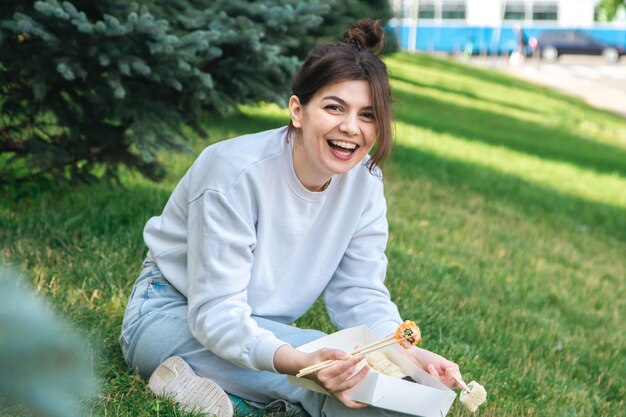 Een jonge vrouw die sushi eet in de parkpicknick in de natuur