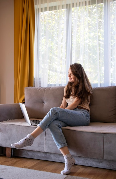 Een jonge vrouw doet online winkelen op afstand Comfortabel huis in een gezellig en stijlvol appartement