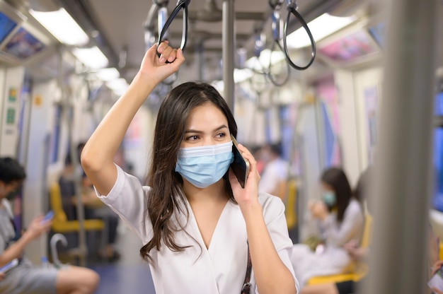 Een jonge vrouw draagt een beschermend masker in de metro, covid-19 bescherming, veiligheidsreizen, nieuw normaal, sociaal distantiëren, veiligheidstransport, reizen onder pandemisch concept.