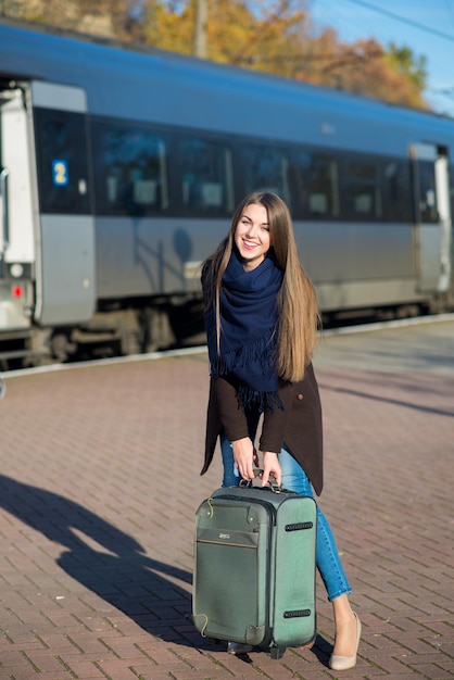 Een jonge vrouw draagt haar koffer op het treinstation