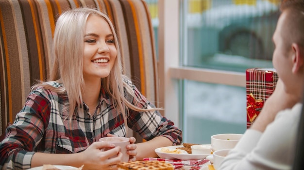 Een jonge vrouw drinkt koffie en praat met haar vriendje in café