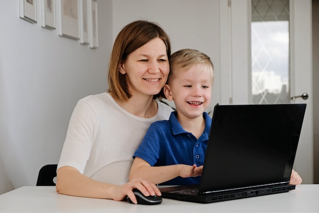 Foto een jonge vrouw en haar zoontje met behulp van laptop