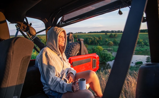 Een jonge vrouw geniet van de zonsondergang terwijl ze in de kofferbak van een suv . zit