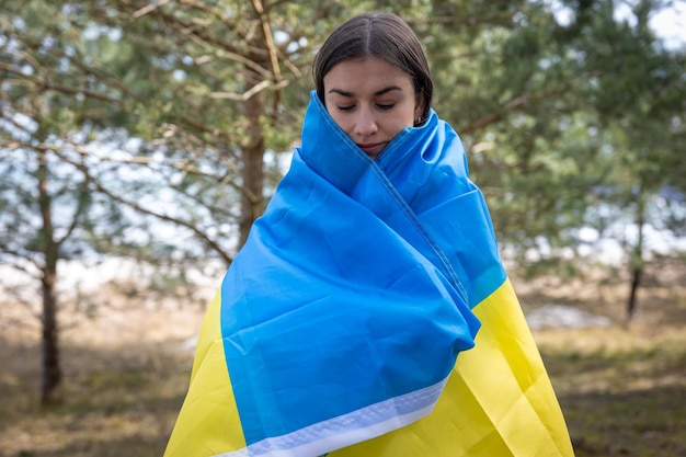 Een jonge vrouw gewikkeld in de vlag van Oekraïne op een onscherpe achtergrond
