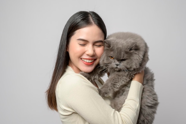Een jonge vrouw houdt een mooie kat vast die met een kat speelt in de studio op een witte achtergrond