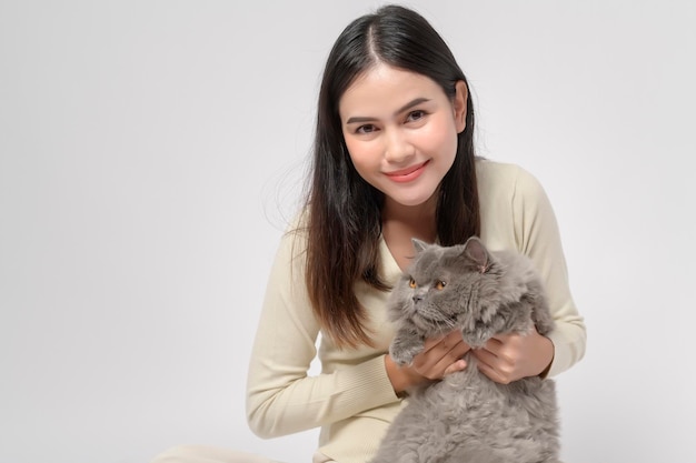 Een jonge vrouw houdt een mooie kat vast die met een kat speelt in de studio op een witte achtergrond