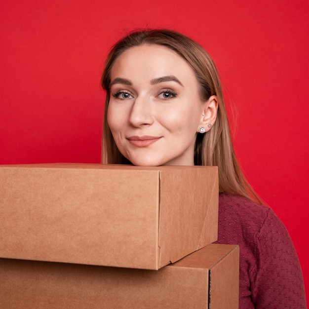 Een jonge vrouw houdt kartonnen dozen op een rode achtergrondVerhuizen naar een ander appartement