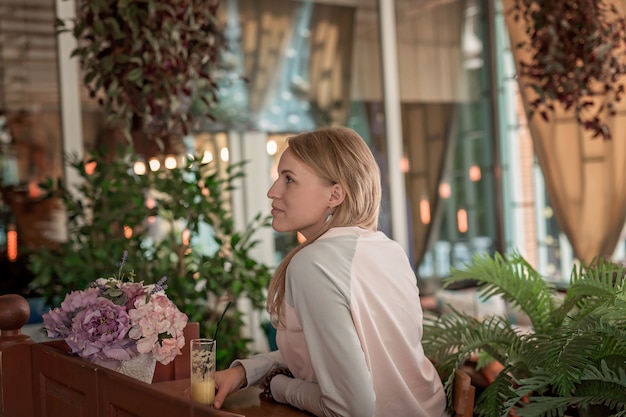 Een jonge vrouw in een café achter de toonbank drinkt drankjes.