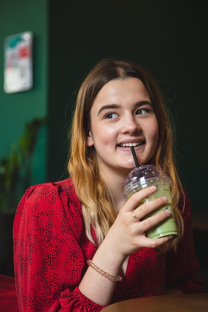 Een jonge vrouw in een café drinkt een groene drank ice latte