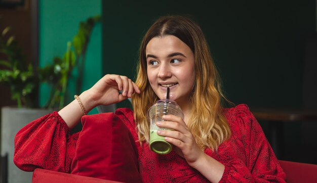 Een jonge vrouw in een café drinkt een groene drank ice latte