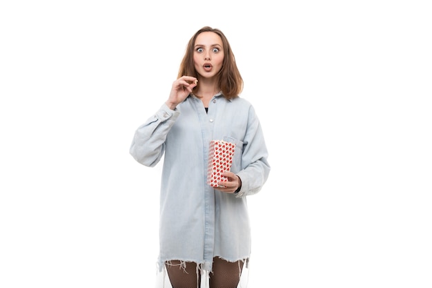 Foto een jonge vrouw in een denimoverhemd eet popcorn