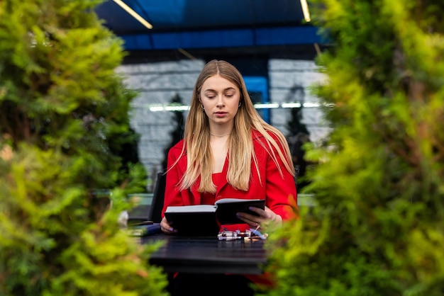 Een jonge vrouw in een jasje werkt op een netbook in een café op het terras