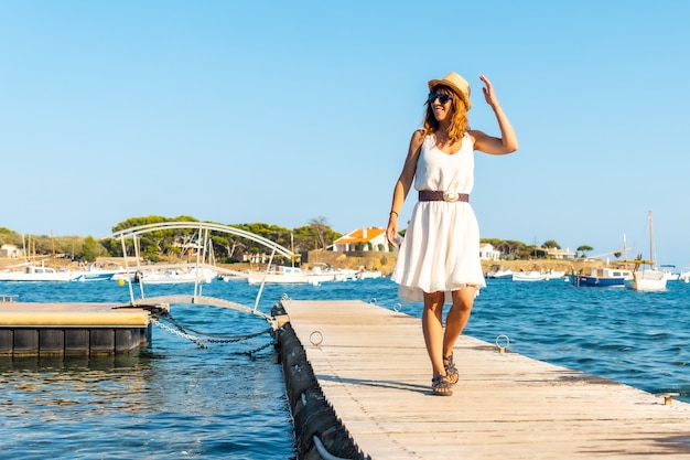 Een jonge vrouw in een jurk in Cadaques wandelen langs een houten loopbrug aan zee, Costa Brava van Catalonië, Gerona, Middellandse Zee. Spanje