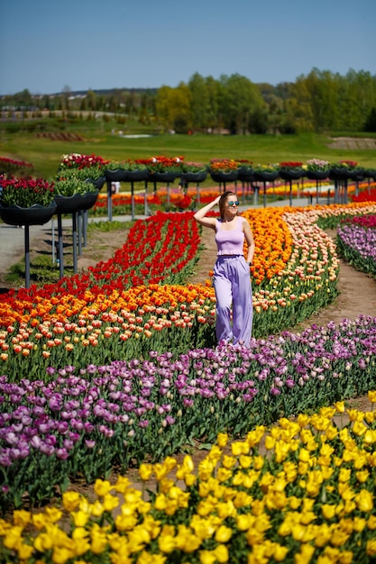 Een jonge vrouw in een roze pak staat in een bloeiend tulpenveld Lentetijd