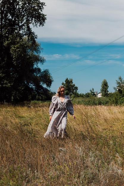 een jonge vrouw in een rustieke jurk loopt ontspannen door een veld in het dorp
