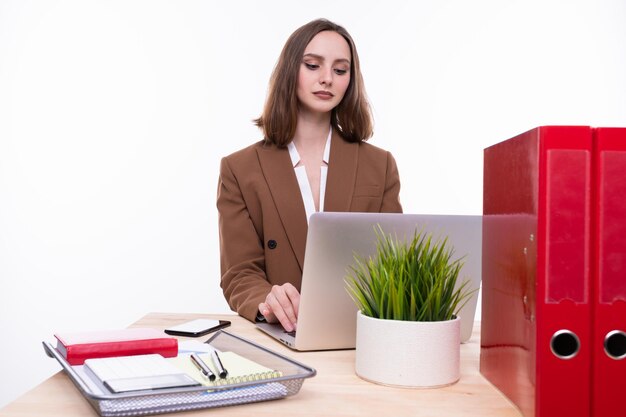 Een jonge vrouw in een stijlvol pak werkt op een laptop aan haar bureau wit geïsoleerd