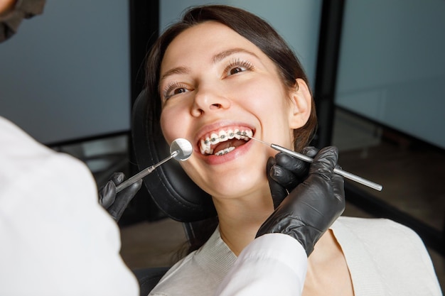 Een jonge vrouw in een tandheelkundige kliniek met een tandarts de vrouw met een beugel lacht het concept van gezond