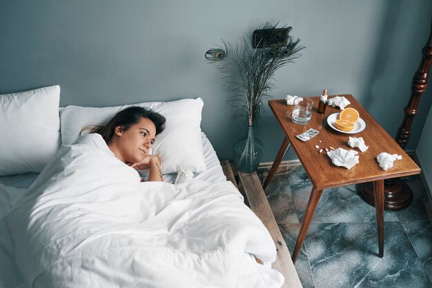 Een jonge vrouw in een ziekbed kijkt vanuit haar ooghoek naar haar medicijnen