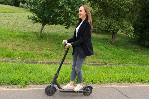 Foto een jonge vrouw in stijlvolle kleding rijdt op een elektrische scooter op een fietspad