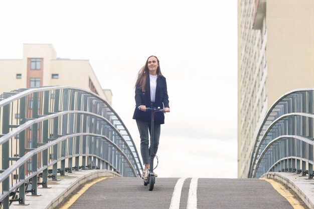 Een jonge vrouw in stijlvolle kleding rijdt op een elektrische scooter op een fietspad