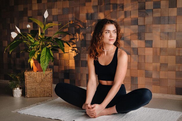 Een jonge vrouw in zwarte kleding doet yoga in een moderne sportschool. Het concept van gezondheid.