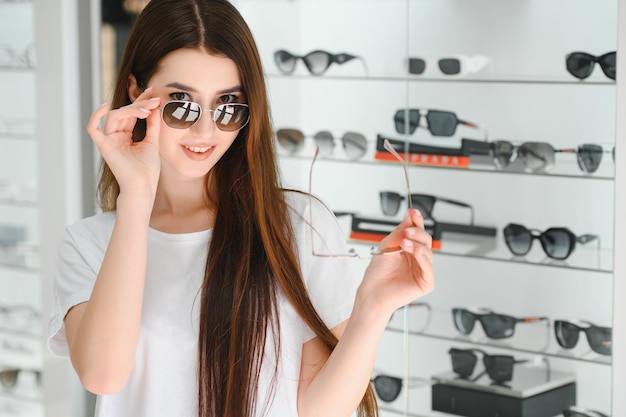 Een jonge vrouw kiest een zonnebril in een optiekwinkel