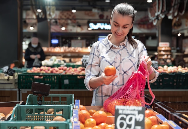 Een jonge vrouw kiest fruit in een supermarkt