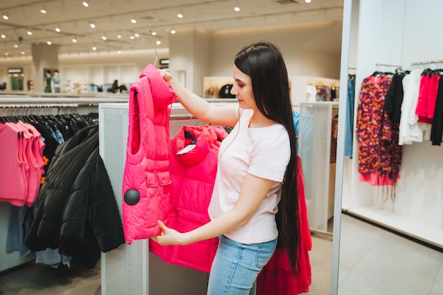 Een jonge vrouw kiest kleding in een winkel