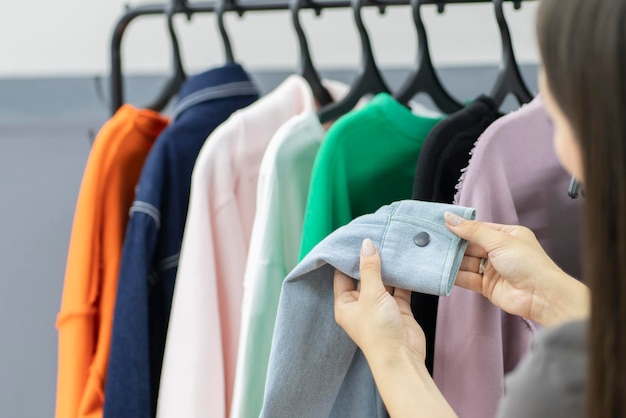 een jonge vrouw kiest kleding op de hanger rack dichtbij