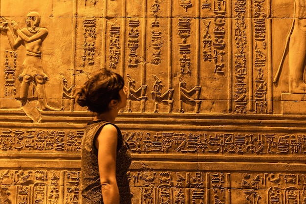 Een jonge vrouw kijkt naar Egyptische tekeningen en hiërogliefen in de tempel van Kom Ombo