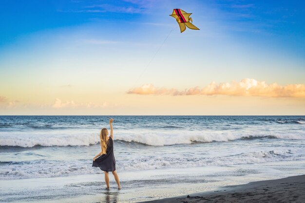 Een jonge vrouw lanceert een vlieger op het strand droomaspiraties toekomstplannen