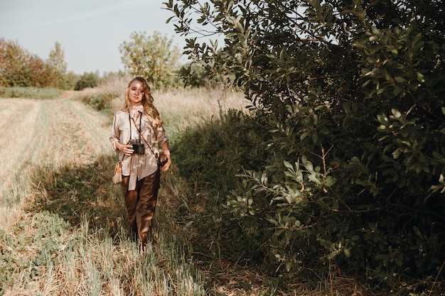 Een jonge vrouw loopt met een retrocamera en maakt foto's van de natuur