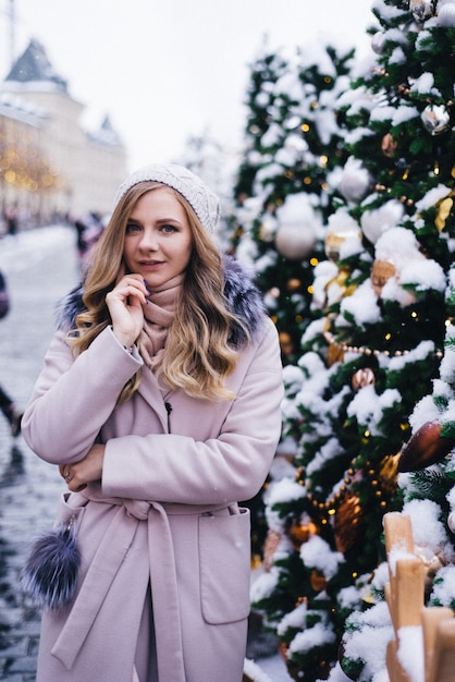 Een jonge vrouw loopt met Kerstmis op het plein bij de versierde kerstbomen. Candy is een lolly in de vorm van een hart.