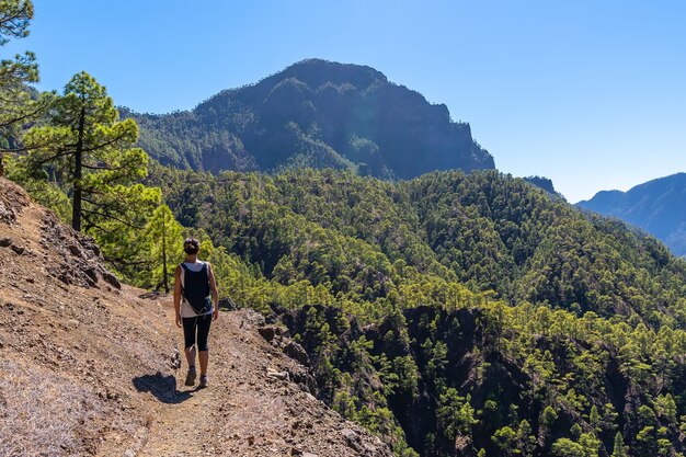 Een jonge vrouw loopt op de tocht naar de top van La Cumbrecita op het pad naast de Caldera de Taburiente motañas, La Palma eiland, Canarische eilanden, Spanje
