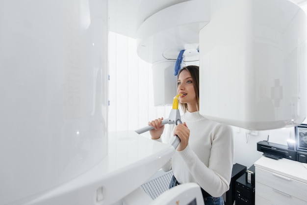 Een jonge vrouw maakt een CT-scan van de kaak een cirkelvormige momentopname van de kaak in de moderne tandheelkunde Tandprothetische behandeling en het bleken van tanden Radiologie panoramische scanner