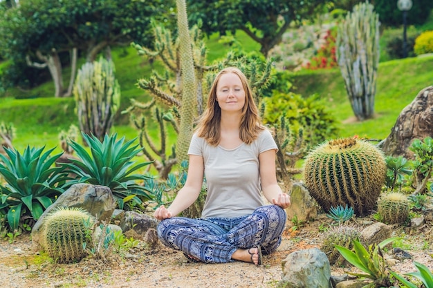 Een jonge vrouw mediteert tussen een cactus