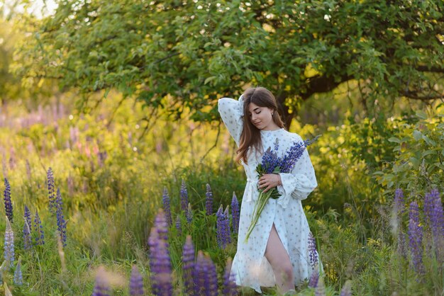 Foto een jonge vrouw met een boeket lupines in een veld