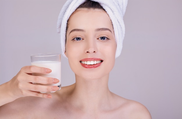 Een jonge vrouw met een brede glimlach houdt een glas melk vast.