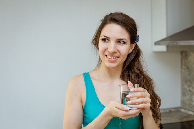 Een jonge vrouw met een glas water in haar handen