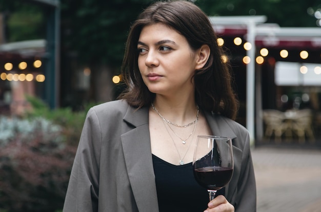 Een jonge vrouw met een glas wijn buiten bij een restaurant